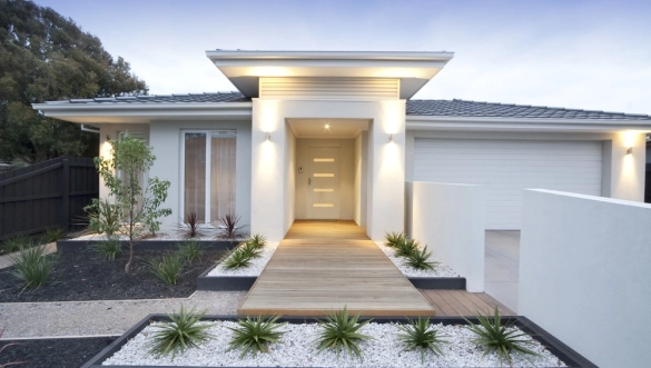 Weißes modernes Einfamilienhaus mit Holzsteg und eingeschalteter Wand-Außenbeleuchtung