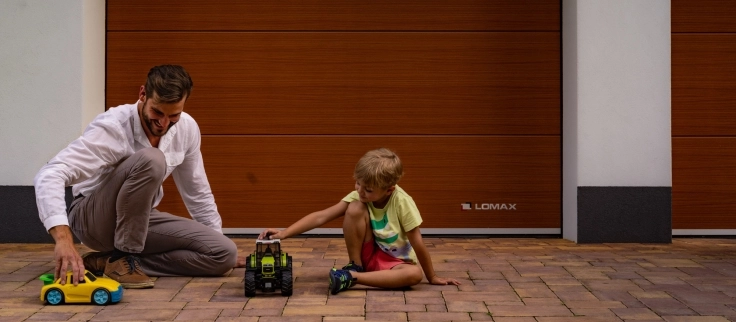 Vater und Sohn mit Spielzeug vor einem LOMAX-Garagentor